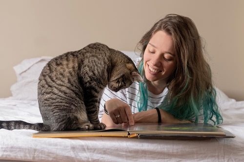 Ragazza con il suo gatto che indica sul libro